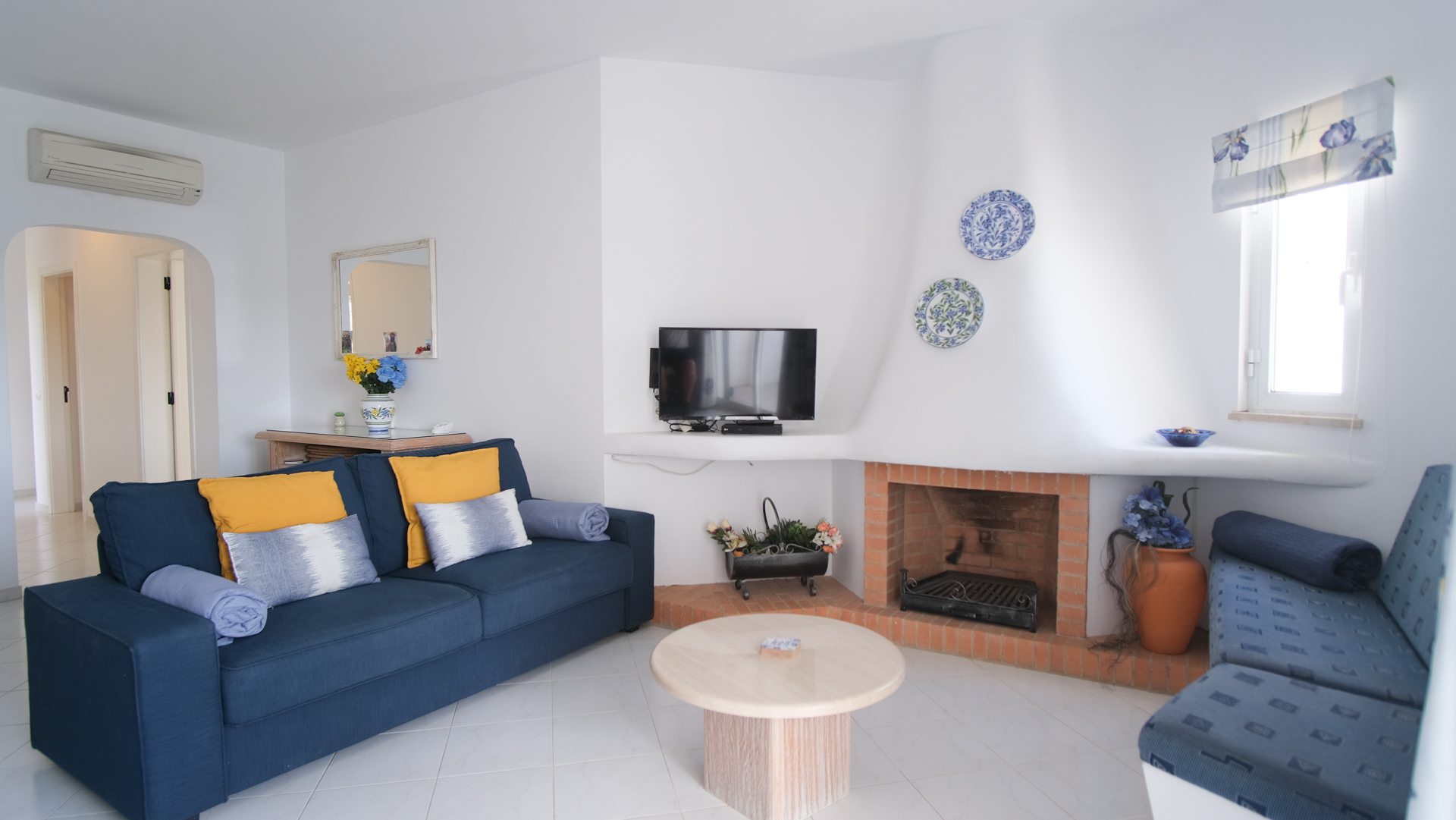 Woonkamer met blauwe bank en open haard